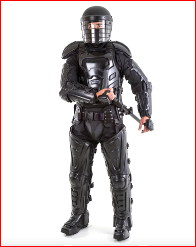 Police officer in SecPro V Complete Riot Gear Suit holding a SecPro 36' Polycarbonate Riot Shield in an urban setting with a blurred crowd, showcasing impact ridges, foam padding, and transparent shield under natural daylight