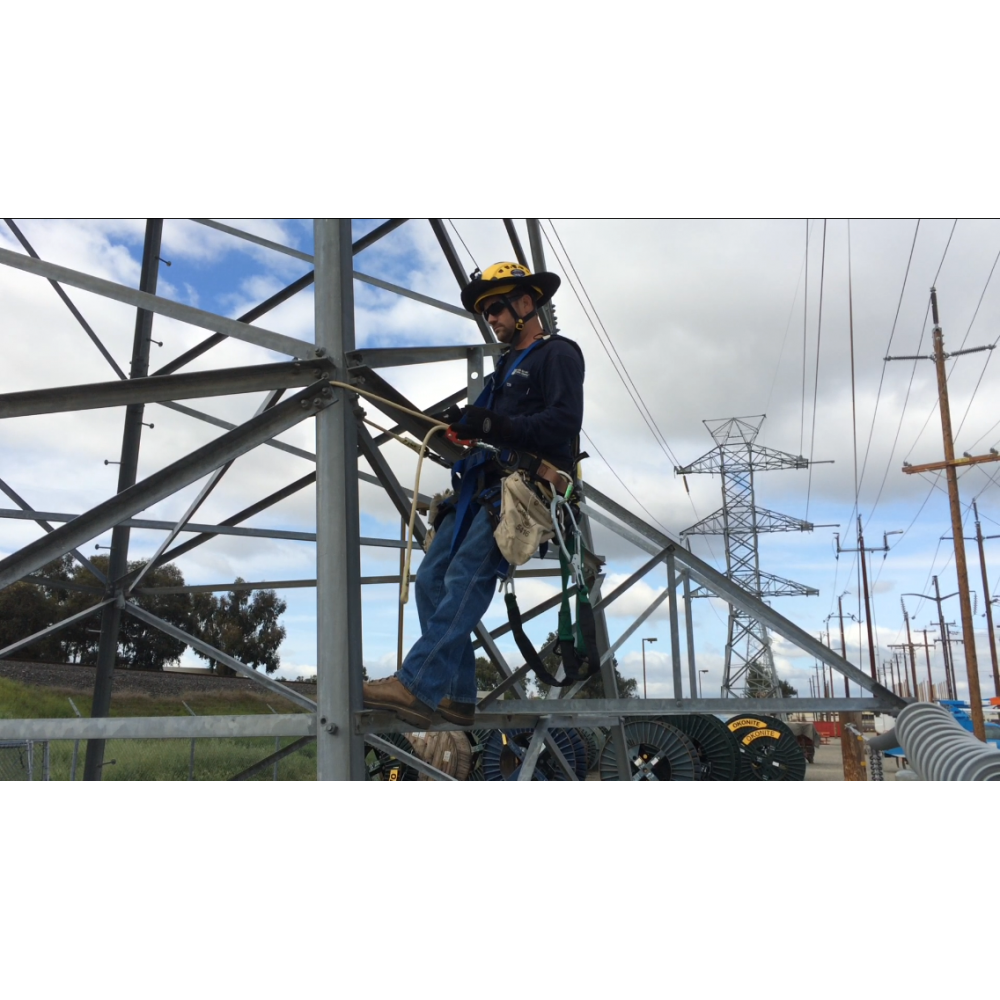 Person working on a metal structure with power lines and towers in the background
