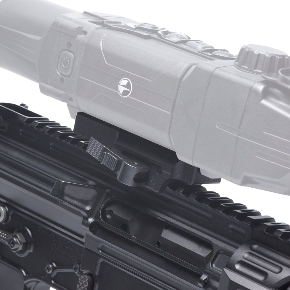 Close-up of a black rifle rail system with a mounted gray sight or scope component, shown against a white background.
