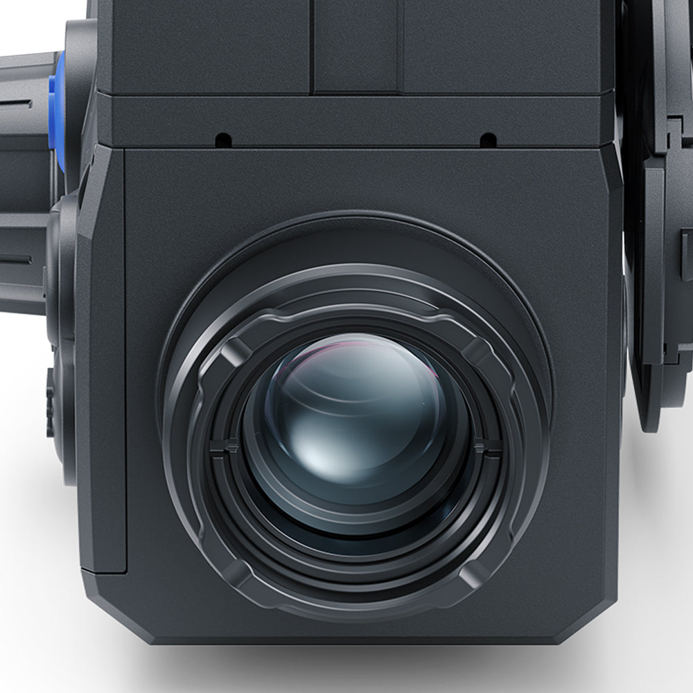 Close-up of a dark gray industrial camera or projector lens assembly with a large circular lens element and metallic ring details.