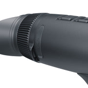 Close-up of a black textured monocular eyepiece focusing ring with a central button, on a solid white background.