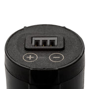 Close-up of the top of a black cylindrical electronic device showing a multi-pin connector with positive and negative terminal markings on a white background.