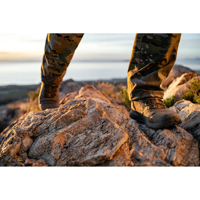 Camouflage pants and Nano X1 Adventure Tactical boots on a rocky landscape