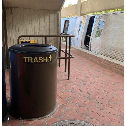 Painted blast containment trash receptacle on transit rail station platform