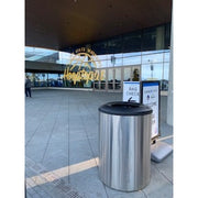 Stainless blast mitigating trash receptacle beside venue bag check station